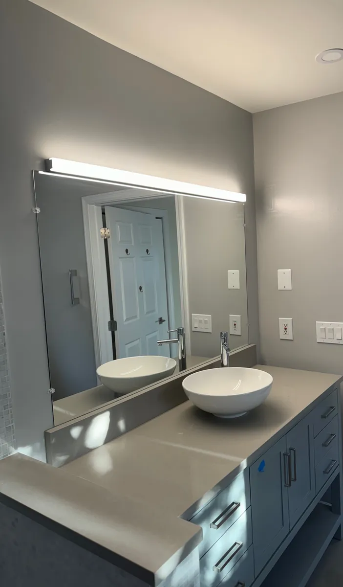 Gray bathroom vanity with a quartz top, white vessel sink and a backlit LED mirror in Stamford, CT