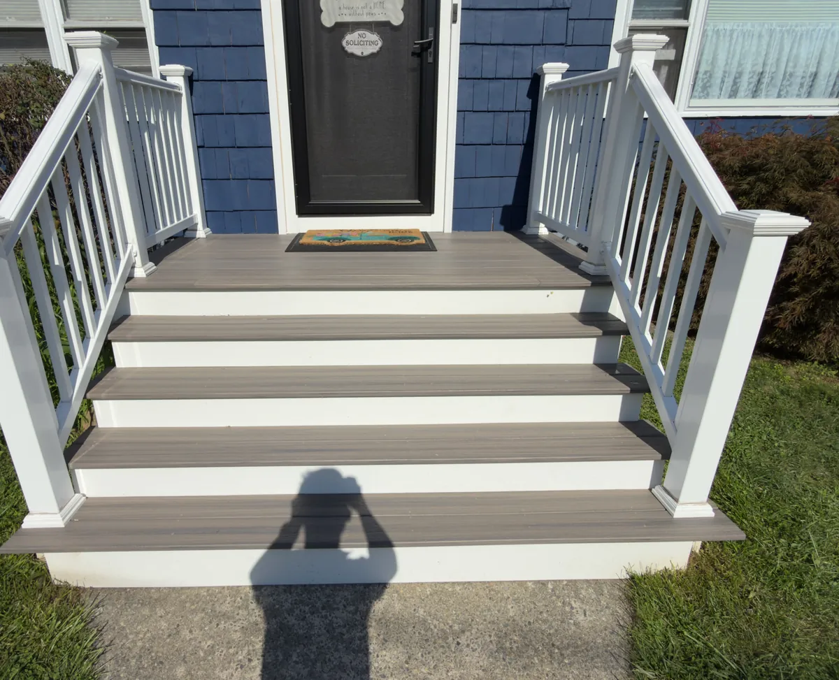 New composite front steps with white vinyl railings at the entry of a navy blue house in Stratford, CT