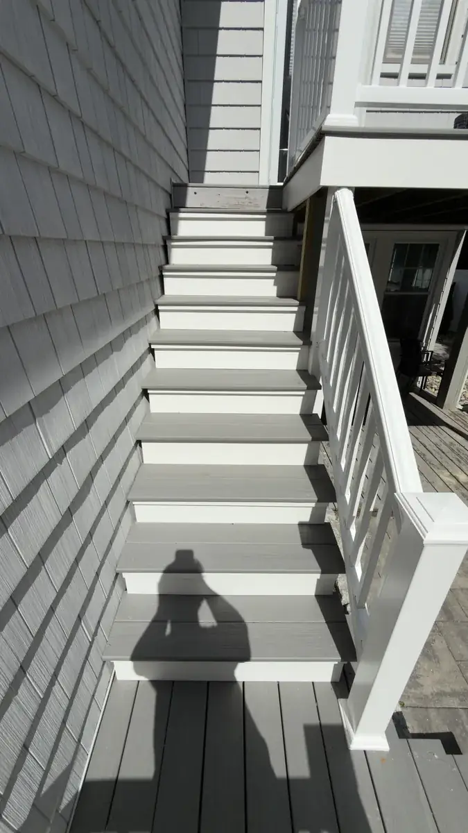 Looking up new gray composite deck stairs with white balusters in Stratford, CT