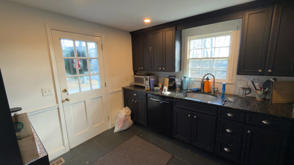 Before: the sink wall with black cabinets, a side door and two windows in Westport, CT