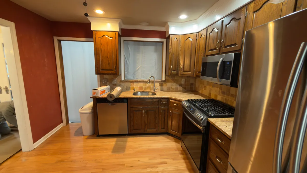 Before: the kitchen with dark oak cabinets, a tile backsplash and a boxed-in window over the sink in Stratford, CT