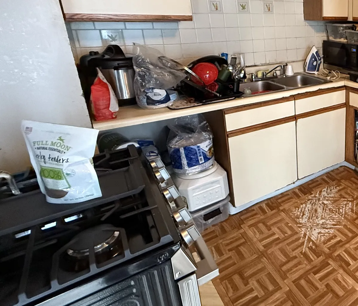 Kitchen before remodeling, with dated cabinets and worn flooring