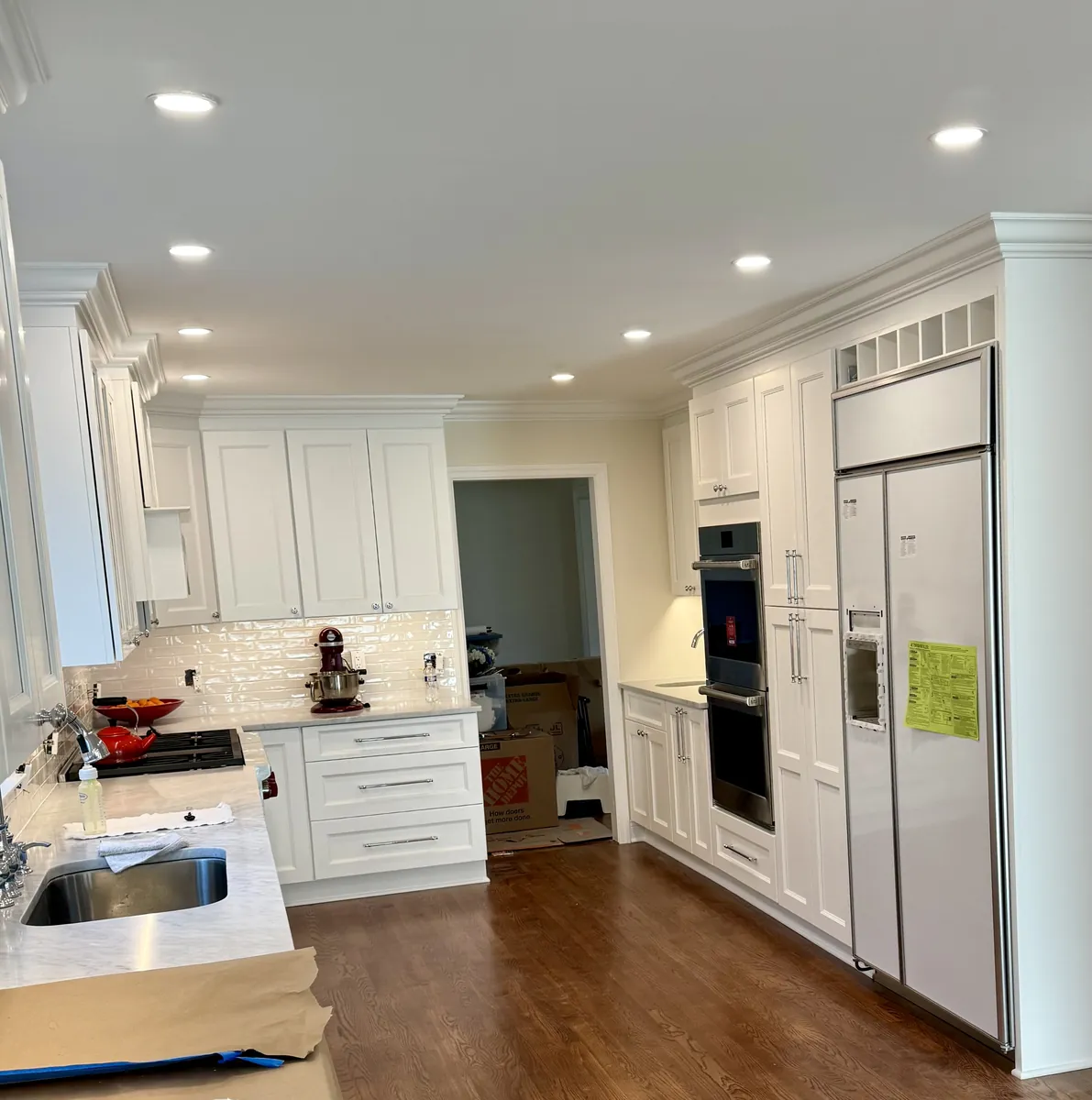 Kitchen with double wall ovens, a built-in refrigerator, white shaker cabinets and recessed lighting in Weston, CT