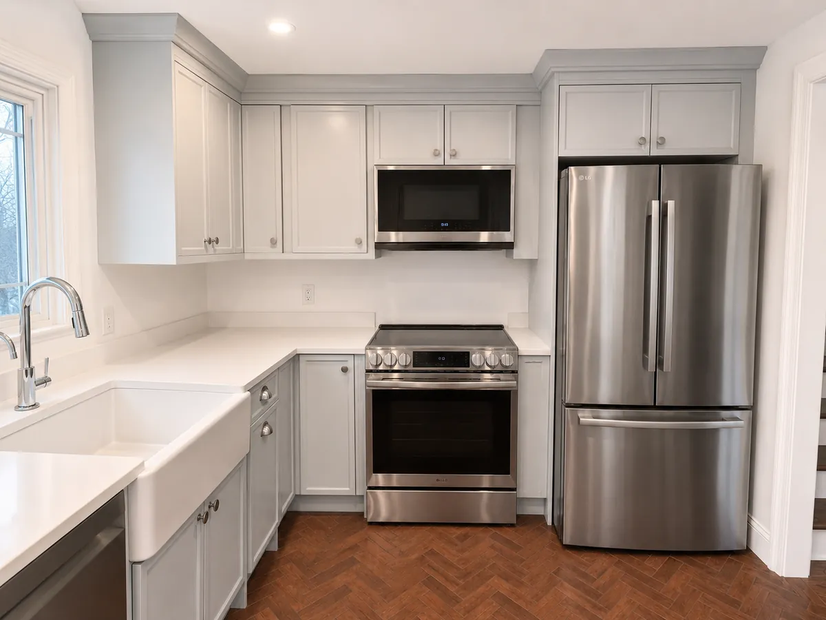 Light gray shaker kitchen with a farmhouse sink, stainless range and herringbone wood floor in Westport, CT