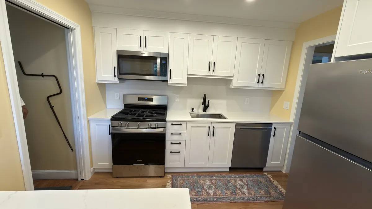 Kitchen run with white shaker cabinets, gas range, over-range microwave and a matte black faucet in Stratford, CT