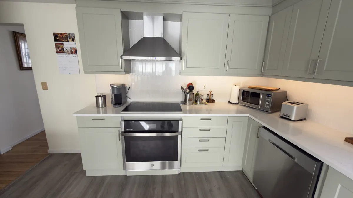 Sage green shaker kitchen with an induction cooktop, stainless hood and white quartz countertops in Fairfield, CT
