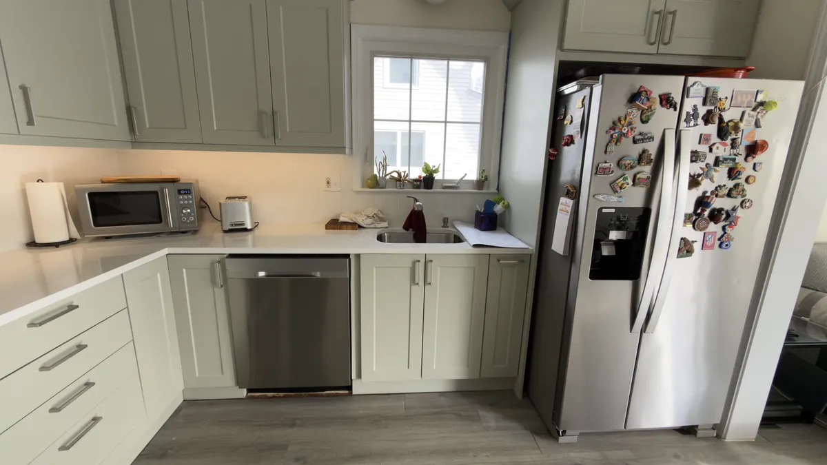 Sage green shaker cabinets with a stainless dishwasher and a window over the sink in Fairfield, CT