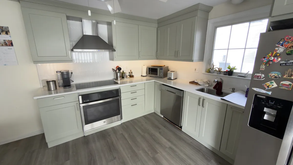 Sage green shaker kitchen with a built-in wall oven, under-cabinet lighting and a window over the sink in Fairfield, CT