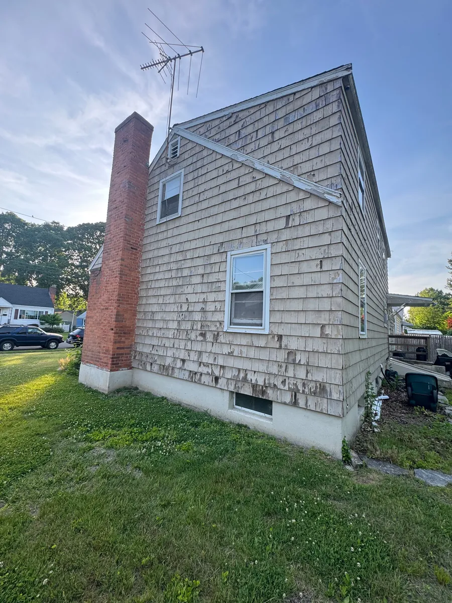 Before: weathered, unpainted cedar shingle siding with a brick chimney in Stratford, CT