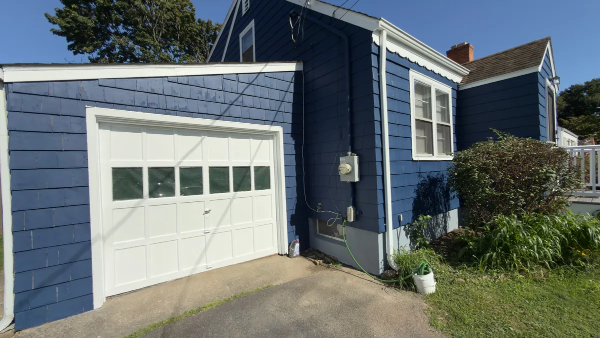House exterior repainted navy blue with crisp white trim and a freshly painted white garage door in Stratford, CT